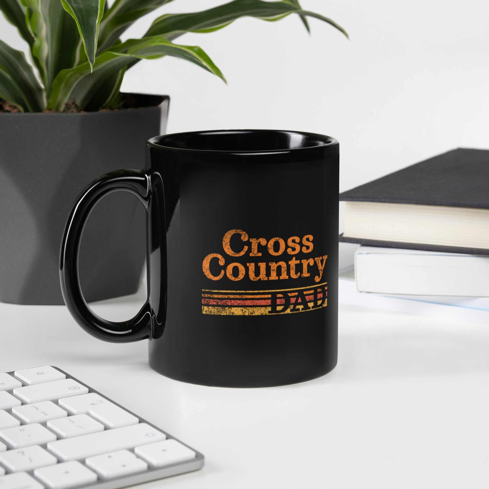a black coffee mug sitting on top of a desk next to a keyboard
